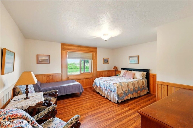22325 Sterling Hwy, Ninilchik, AK 99639 - bedroom featuring wainscoting, light wood-style flooring, wooden walls, and a textured ceiling