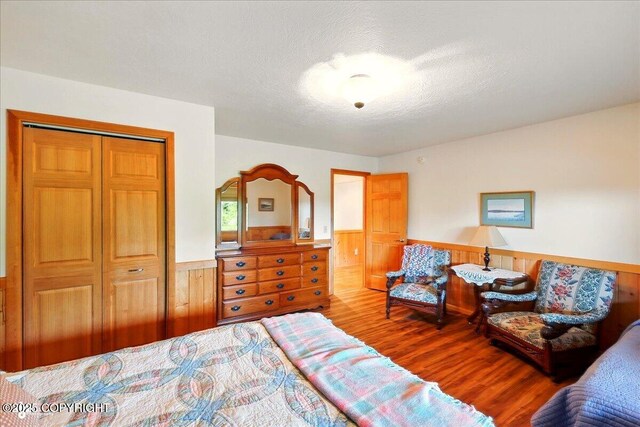 22325 Sterling Hwy, Ninilchik, AK 99639 - bedroom featuring wainscoting, wood finished floors, a closet, wood walls, and a textured ceiling