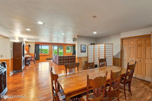 22325 Sterling Hwy, Ninilchik, AK 99639 - dining area featuring a wainscoted wall, light wood-style floors, recessed lighting, a textured ceiling, and wood walls