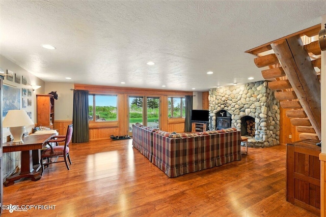 22325 Sterling Hwy, Ninilchik, AK 99639 - living area featuring a textured ceiling, wood finished floors, recessed lighting, a wainscoted wall, and a stone fireplace