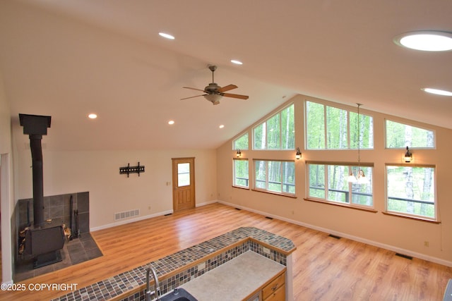 11838 N Hagion Shores Dr, Willow, AK 99688 - unfurnished living room with a wood stove, a ceiling fan, light wood-type flooring, baseboards, and a sink