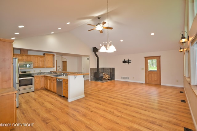 11838 N Hagion Shores Dr, Willow, AK 99688 - kitchen with stainless steel appliances, open floor plan, a wood stove, a peninsula, and ceiling fan