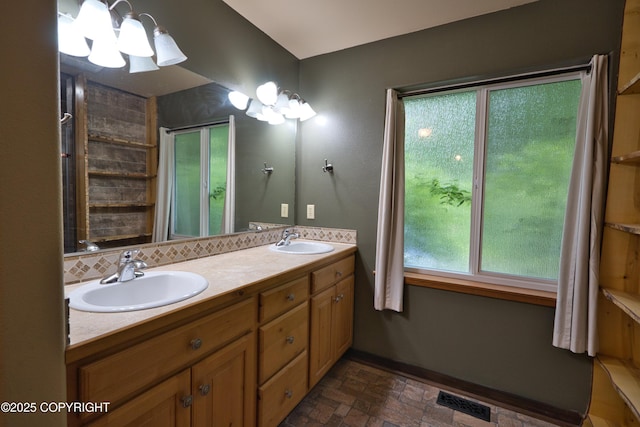 11838 N Hagion Shores Dr, Willow, AK 99688 - bathroom featuring double vanity, a chandelier, baseboards, and stone finish floors