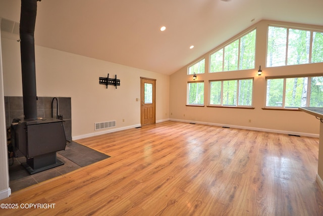 11838 N Hagion Shores Dr, Willow, AK 99688 - unfurnished living room with high vaulted ceiling, light wood finished floors, a wood stove, baseboards, and recessed lighting