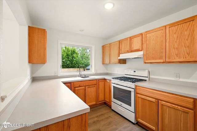 557 N Glenn Hwy, Palmer, AK 99645 - kitchen with white range with gas stovetop, under cabinet range hood, a sink, light countertops, and light wood-type flooring