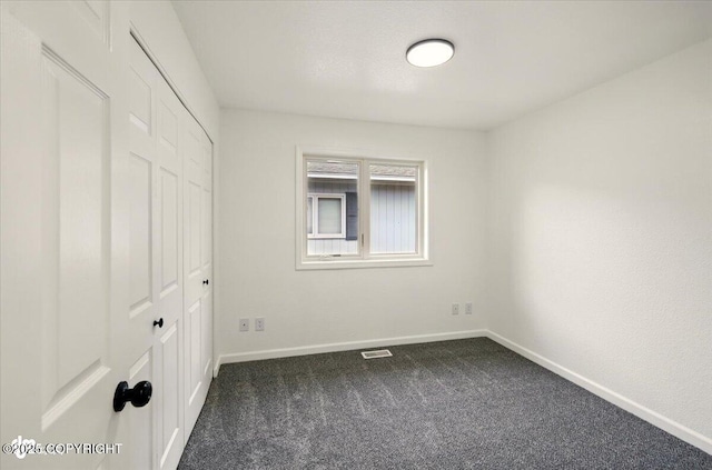 557 N Glenn Hwy, Palmer, AK 99645 - unfurnished bedroom featuring dark carpet, a closet, and baseboards