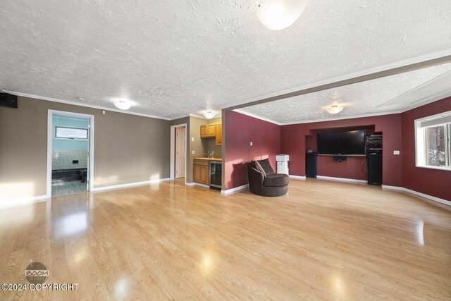4745 Manytell Ave, Anchorage, AK 99516 - unfurnished living room with light wood-style floors, a textured ceiling, beverage cooler, crown molding, and baseboards