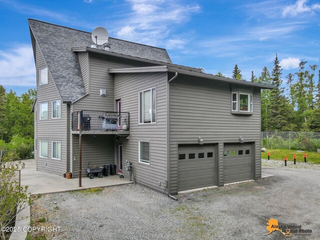 4745 Manytell Ave, Anchorage, AK 99516 - back of house with an attached garage, gravel driveway, a shingled roof, and a balcony