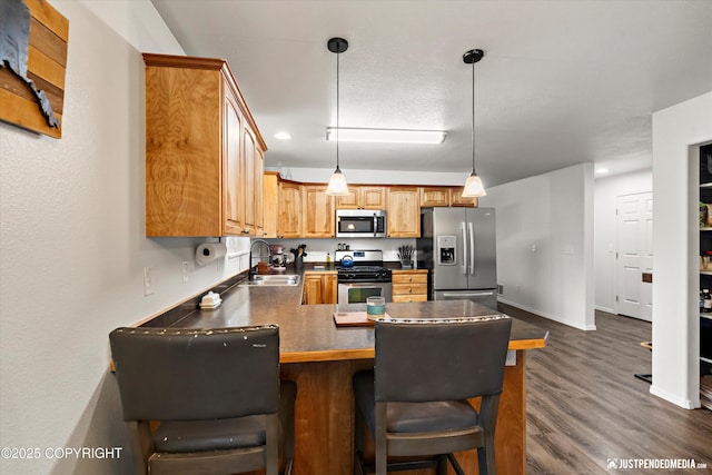 7490 W Rodney Cir, Wasilla, AK 99623 - kitchen with stainless steel appliances, a sink, a peninsula, dark wood-type flooring, and decorative light fixtures