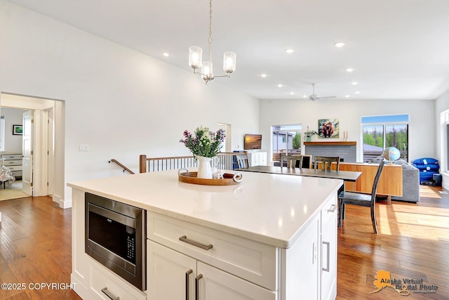5466 Sandhill Loop, Anchorage, AK 99502 - kitchen featuring stainless steel microwave, open floor plan, hardwood / wood-style flooring, ceiling fan, and recessed lighting