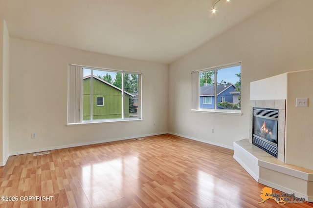 2598 Brookshire Loop # 27, Anchorage, AK 99504 - unfurnished living room with healthy amount of natural light, light wood-type flooring, a fireplace, and lofted ceiling