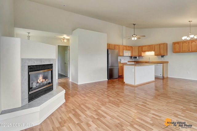 2598 Brookshire Loop # 27, Anchorage, AK 99504 - kitchen with white appliances, open floor plan, a fireplace, high vaulted ceiling, and light wood finished floors