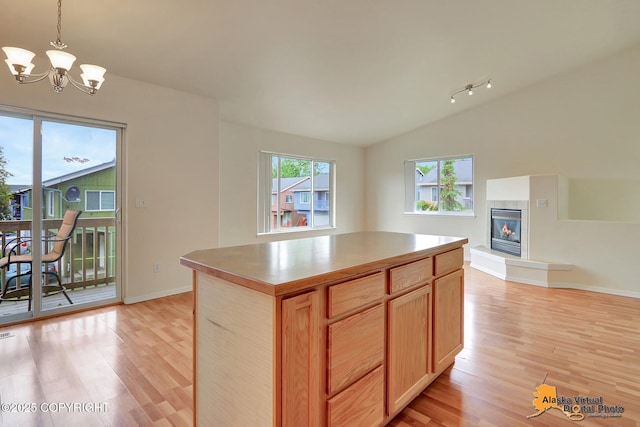 2598 Brookshire Loop # 27, Anchorage, AK 99504 - kitchen with light wood-style floors, lofted ceiling, a chandelier, a tile fireplace, and a kitchen island