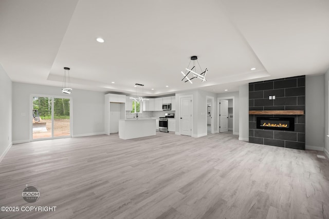 8328 S Ira Dr, Wasilla, AK 99623 - unfurnished living room with a raised ceiling, recessed lighting, light wood finished floors, and a chandelier