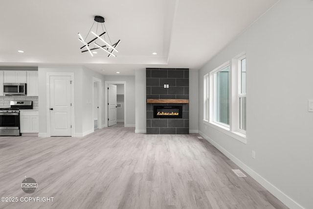8328 S Ira Dr, Wasilla, AK 99623 - unfurnished living room featuring recessed lighting, light wood finished floors, a fireplace, and a chandelier