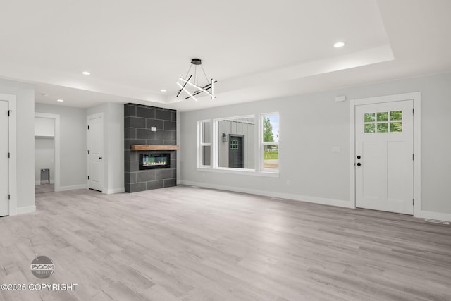 8328 S Ira Dr, Wasilla, AK 99623 - unfurnished living room featuring a chandelier, a raised ceiling, recessed lighting, light wood-style flooring, and a fireplace