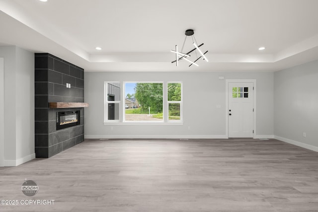 8328 S Ira Dr, Wasilla, AK 99623 - unfurnished living room featuring a tray ceiling, a tile fireplace, recessed lighting, and wood finished floors