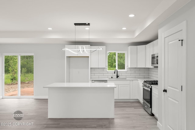 8328 S Ira Dr, Wasilla, AK 99623 - kitchen featuring appliances with stainless steel finishes, decorative backsplash, a center island, light wood-style flooring, and recessed lighting