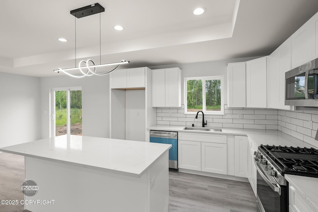 8328 S Ira Dr, Wasilla, AK 99623 - kitchen featuring appliances with stainless steel finishes, tasteful backsplash, a center island, a tray ceiling, and recessed lighting