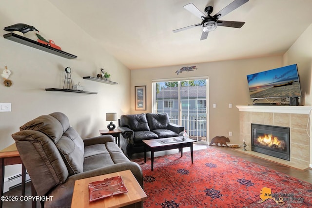 201 E Danna Ave Unit D, Wasilla, AK 99654 - living room featuring wood finished floors, a tiled fireplace, a ceiling fan, lofted ceiling, and a baseboard heating unit