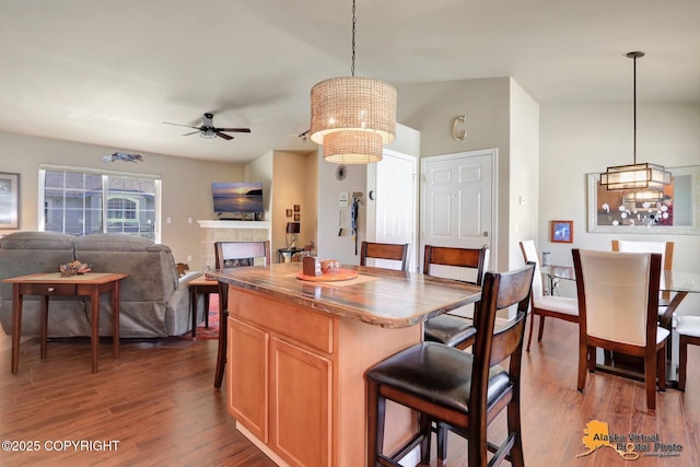 201 E Danna Ave Unit D, Wasilla, AK 99654 - kitchen featuring dark wood-type flooring, a kitchen breakfast bar, ceiling fan, a tile fireplace, and decorative light fixtures