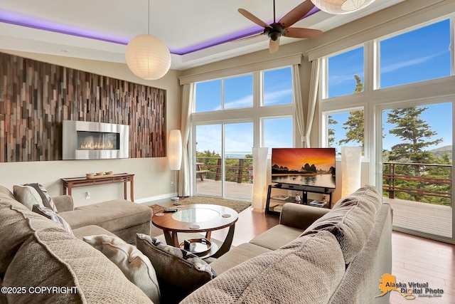 17132 Carl St, Anchorage, AK 99516 - living room with a towering ceiling, a ceiling fan, wood finished floors, a glass covered fireplace, and baseboards