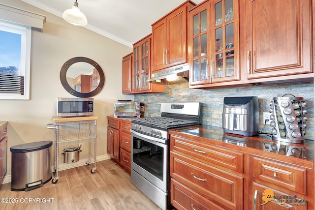 17132 Carl St, Anchorage, AK 99516 - kitchen featuring under cabinet range hood, stainless steel appliances, brown cabinetry, crown molding, and baseboards