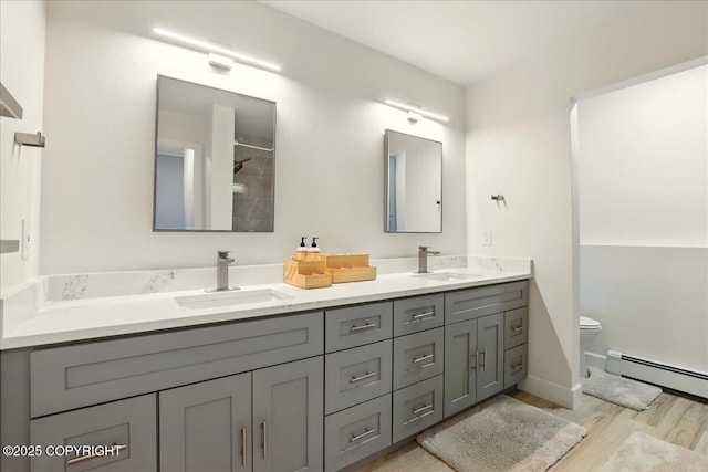 9701 Homestead Trl, Anchorage, AK 99507 - full bath featuring baseboard heating, double vanity, wood finished floors, toilet, and a shower