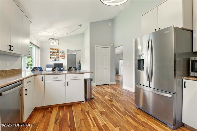 9701 Homestead Trl, Anchorage, AK 99507 - kitchen with appliances with stainless steel finishes, lofted ceiling, a peninsula, white cabinets, and light wood finished floors