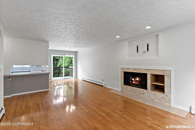 11730 Nix Ct, Anchorage, AK 99515 - unfurnished living room featuring a baseboard radiator, wood finished floors, a textured ceiling, a tile fireplace, and a chandelier
