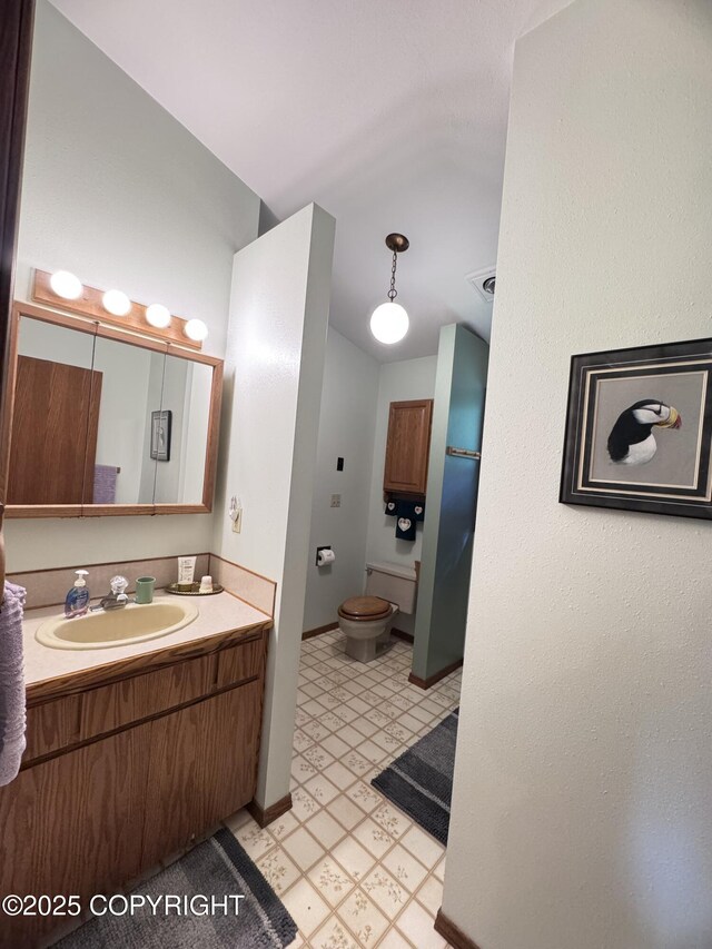 34008 Orlander Ave, Seward, AK 99664 - bathroom with tile patterned floors, toilet, vanity, baseboards, and lofted ceiling