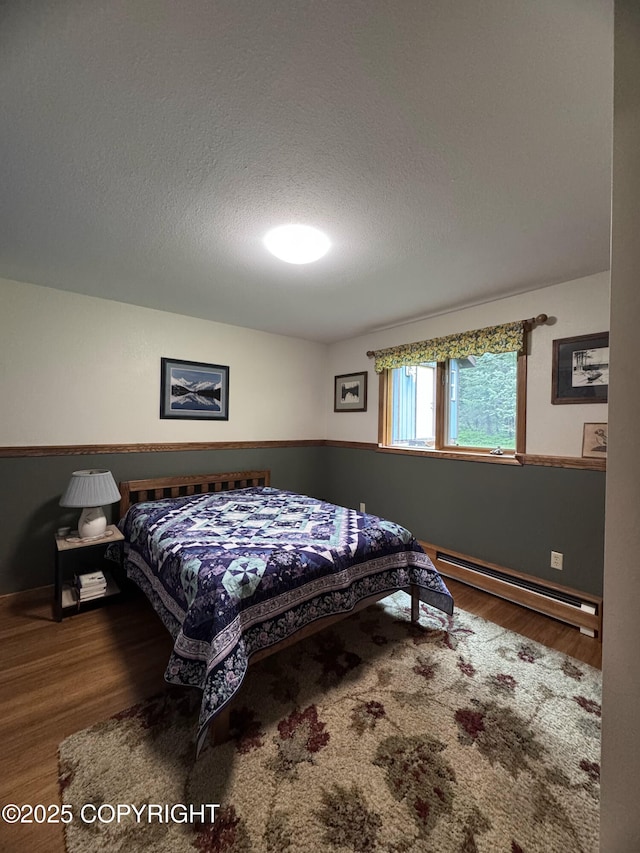 34008 Orlander Ave, Seward, AK 99664 - bedroom featuring baseboard heating, wood finished floors, a textured ceiling, and baseboards