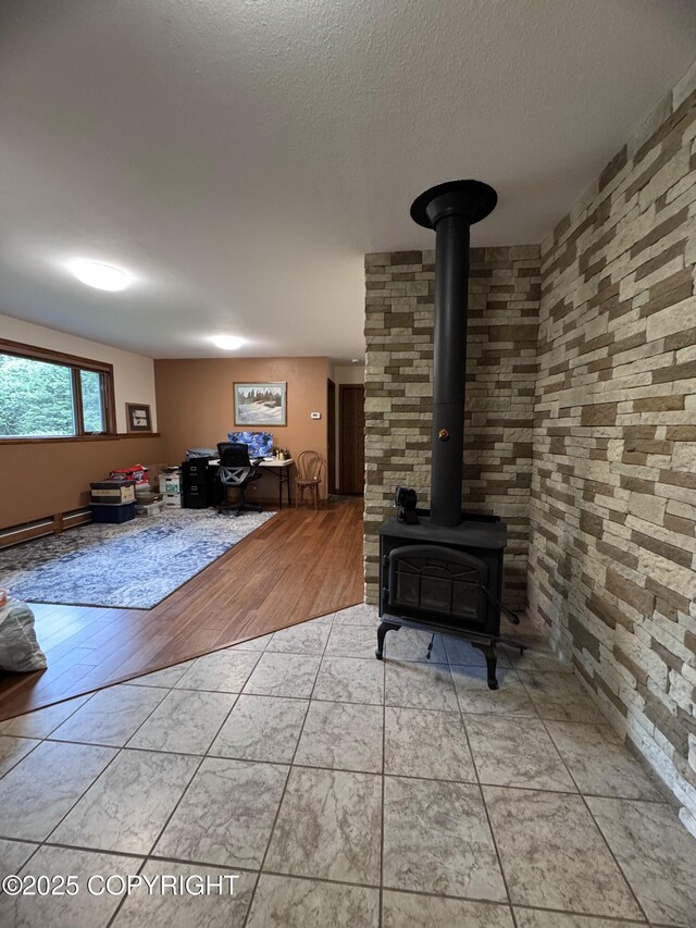 34008 Orlander Ave, Seward, AK 99664 - living room with a wood stove, a baseboard heating unit, and a textured ceiling