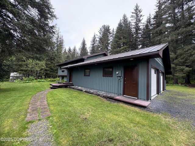 34008 Orlander Ave, Seward, AK 99664 - view of front facade featuring board and batten siding, a front lawn, metal roof, a garage, and an outdoor structure