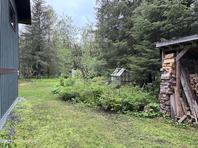 34008 Orlander Ave, Seward, AK 99664 - view of green lawn with a greenhouse, an outdoor structure, and a wooded view