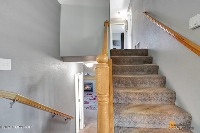 962 S Rebecca Dr, Palmer, AK 99645 - stairs featuring a warm lit fireplace, a textured wall, and carpet floors