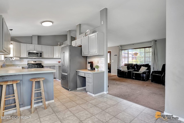 962 S Rebecca Dr, Palmer, AK 99645 - kitchen with stainless steel appliances, lofted ceiling, light carpet, decorative backsplash, and light countertops
