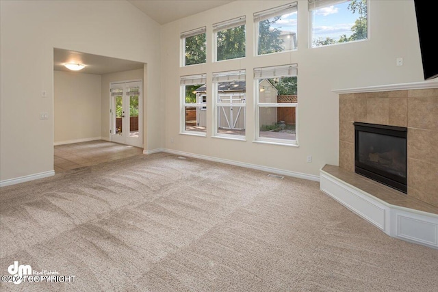 17231 Alice Loop, Eagle River, AK 99577 - unfurnished living room with carpet floors, a tile fireplace, high vaulted ceiling, and french doors