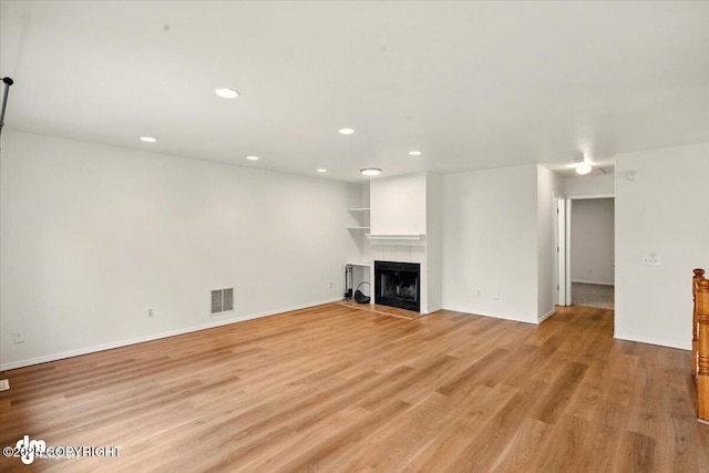 10270 Sextant Cir, Anchorage, AK 99515 - unfurnished living room featuring recessed lighting, light wood-style floors, a tiled fireplace, and baseboards