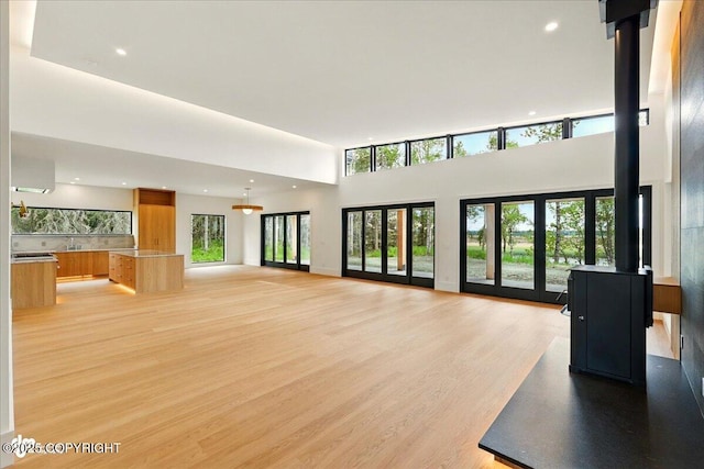 1308 Cunningham Ct, Kenai, AK 99611 - unfurnished living room featuring light wood-style floors, a towering ceiling, and recessed lighting