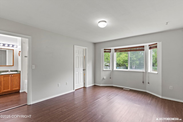 4470 E Birchwood Dr, Wasilla, AK 99654 - unfurnished bedroom featuring dark wood-style floors, baseboards, connected bathroom, and a sink