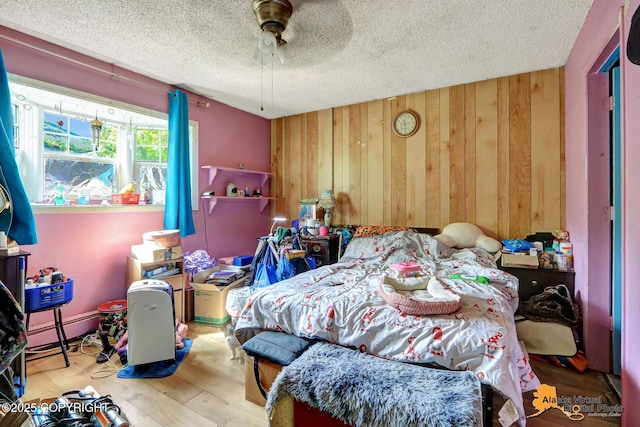 7510 Peck Ave, Anchorage, AK 99504 - bedroom with baseboard heating, a textured ceiling, wood finished floors, wooden walls, and ceiling fan