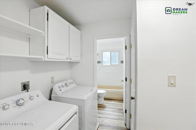 1918 Juneau Dr, Anchorage, AK 99501 - washroom with cabinet space, washing machine and dryer, light wood-style floors, and a textured wall