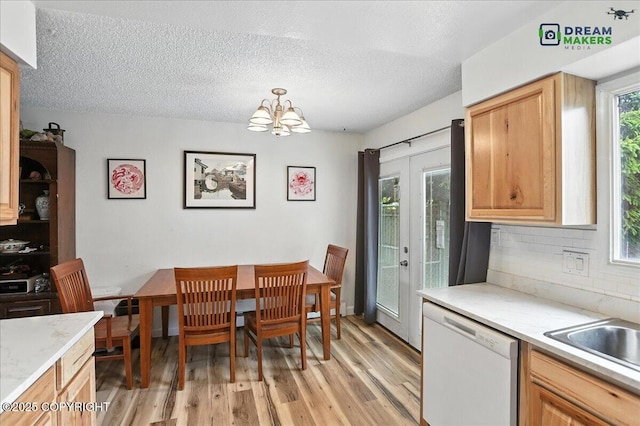 1918 Juneau Dr, Anchorage, AK 99501 - kitchen with dishwasher, light wood-style flooring, light countertops, tasteful backsplash, and a chandelier
