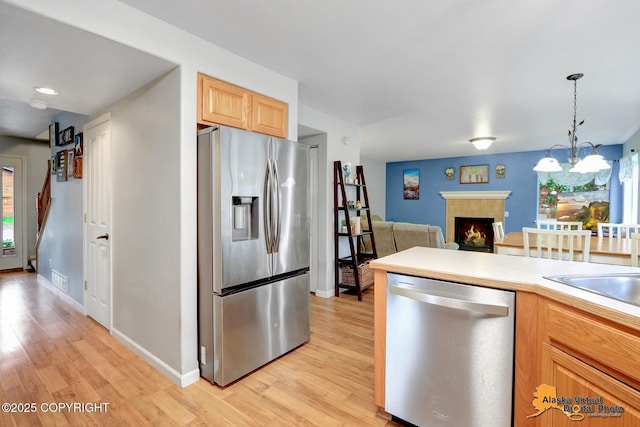 18924 Third St, Eagle River, AK 99577 - kitchen with appliances with stainless steel finishes, light wood finished floors, light countertops, and a tiled fireplace