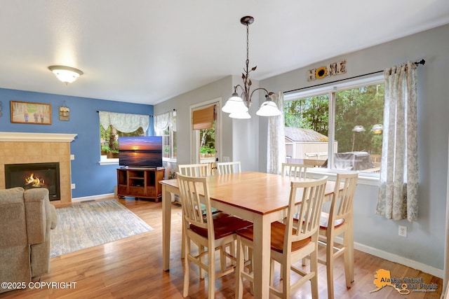 18924 Third St, Eagle River, AK 99577 - dining room with a chandelier, plenty of natural light, light wood-style flooring, and a fireplace