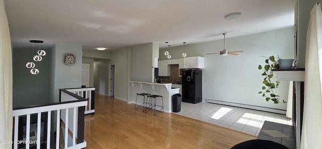 6905 Cape Lisburne Loop, Anchorage, AK 99504 - kitchen featuring a baseboard heating unit, freestanding refrigerator, a kitchen breakfast bar, tasteful backsplash, and white cabinetry