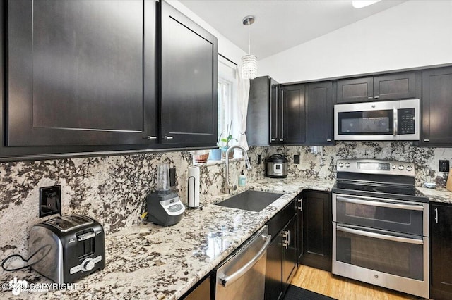 8968 Little Brook St, Anchorage, AK 99507 - kitchen with stainless steel appliances, decorative backsplash, light stone counters, light wood-style flooring, and vaulted ceiling