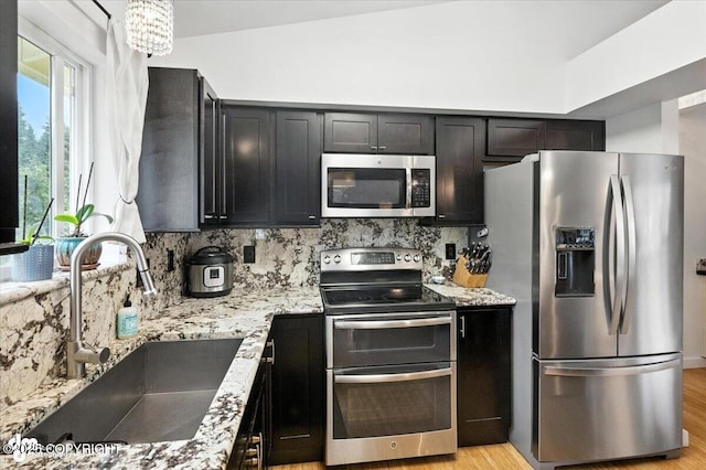8968 Little Brook St, Anchorage, AK 99507 - kitchen featuring appliances with stainless steel finishes, tasteful backsplash, light stone countertops, and light wood-type flooring