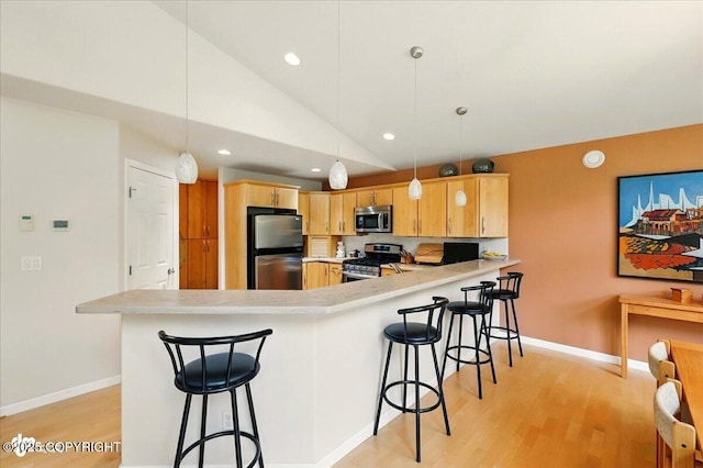 48585 Runners Ave, Soldotna, AK 99669 - kitchen with stainless steel appliances, a peninsula, lofted ceiling, light wood-type flooring, and light countertops